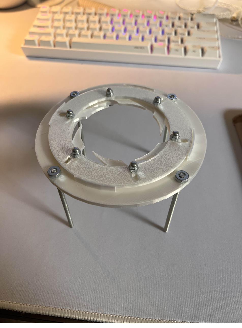 Later 3D printed iris prototype raised on metal standoffs on a desk.