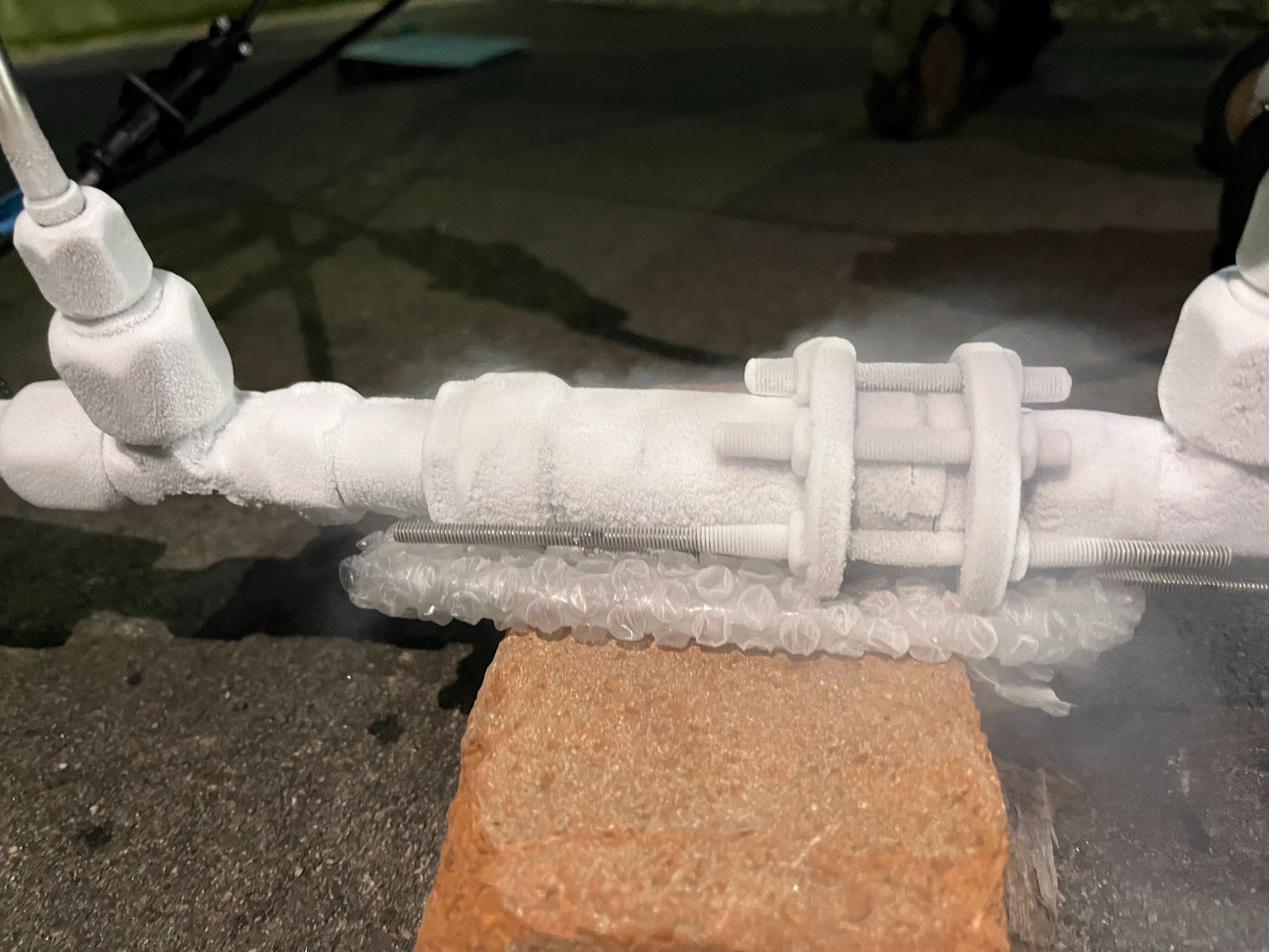 The LOx fill valve covered in frost during a cryogenic flow test, nitrogen vapour venting around it