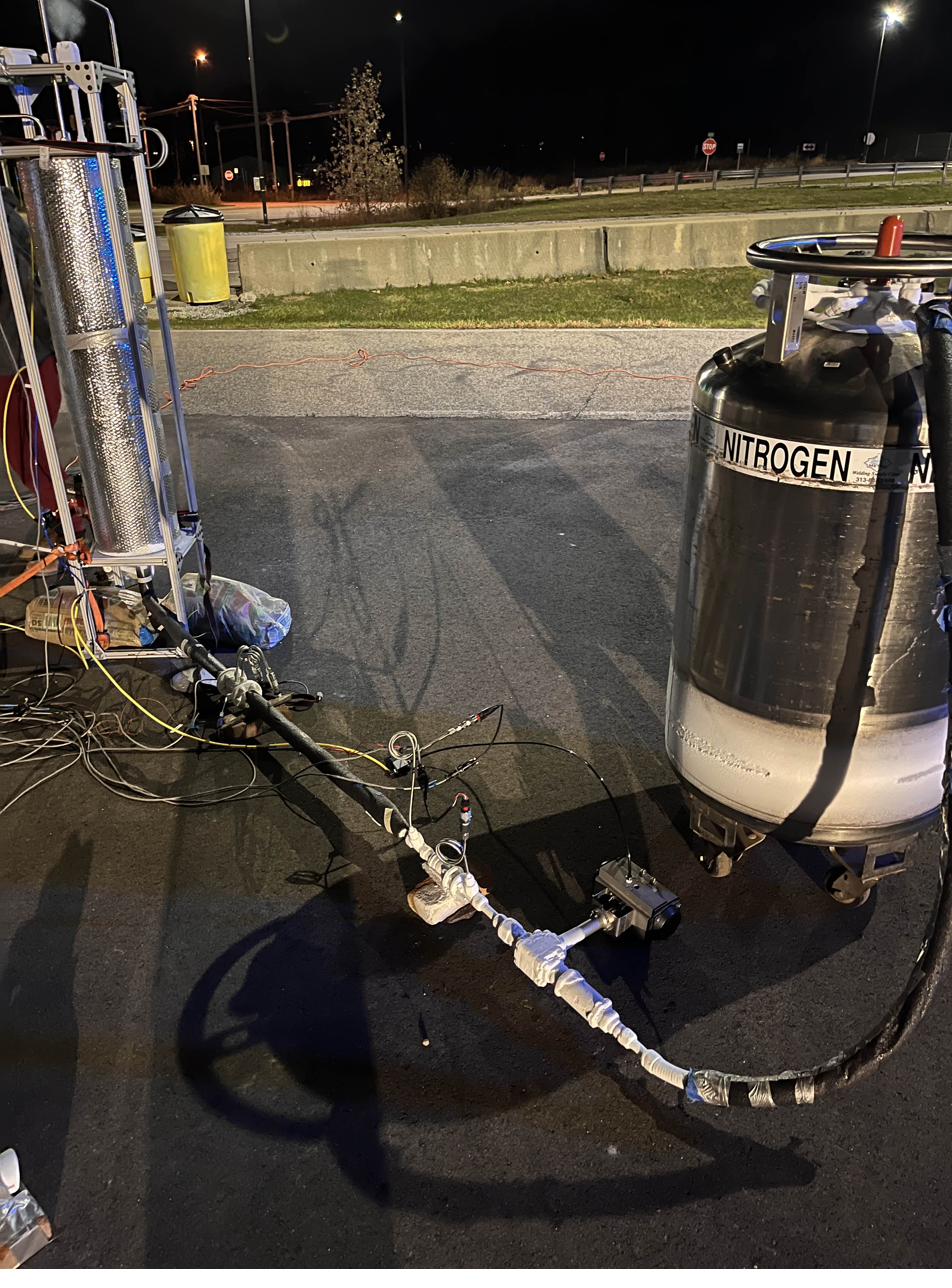 Liquid nitrogen flow test setup at night: a nitrogen dewar and pressure vessel plumbed to the valve on a paved lot.
