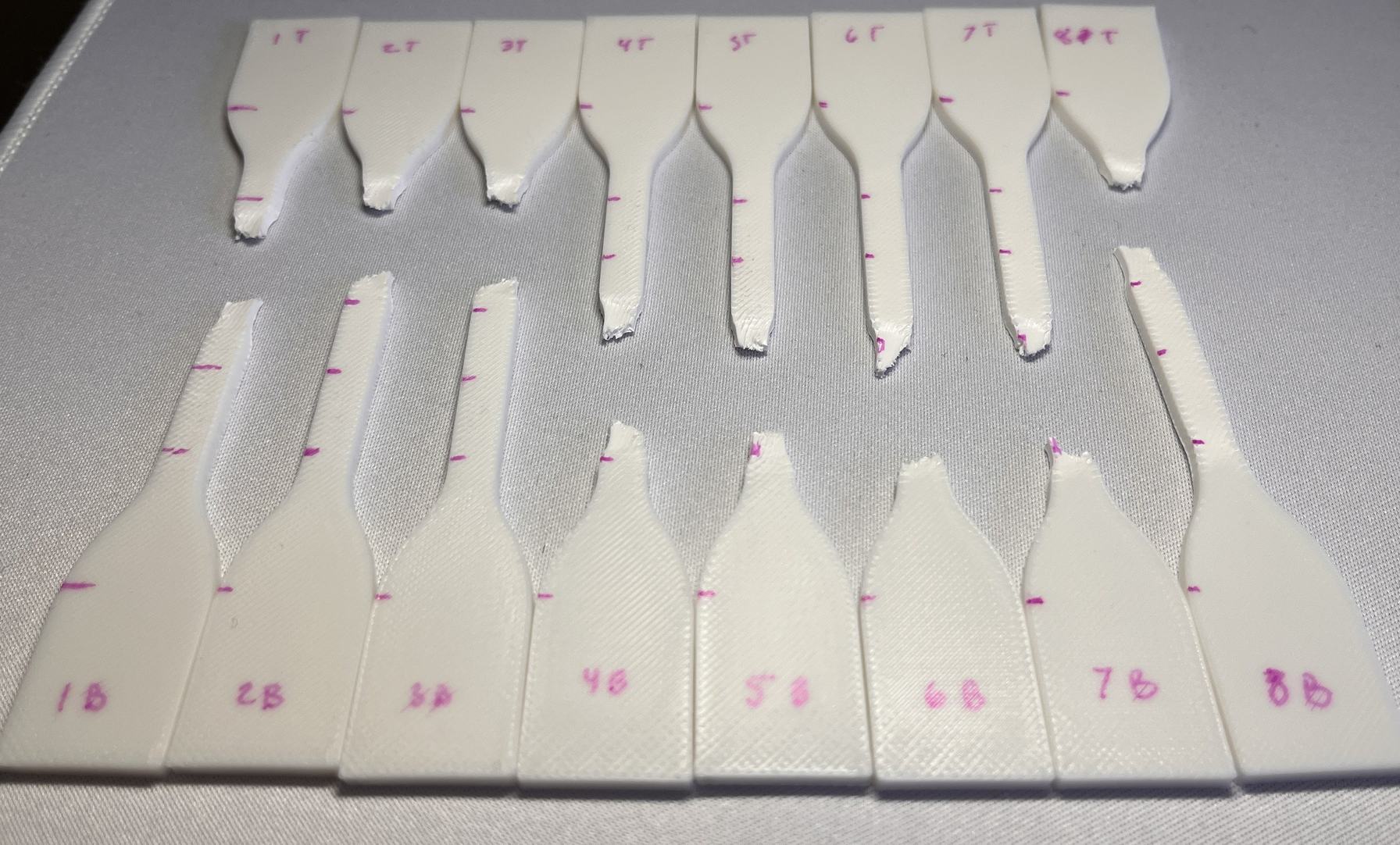ASTM D638 Type IV tensile specimens after failure, showing necking in the virgin PLA gauge length